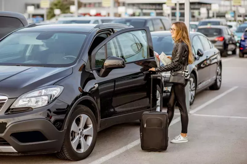 happy woman traveling with suitcase near the rental car outdoors