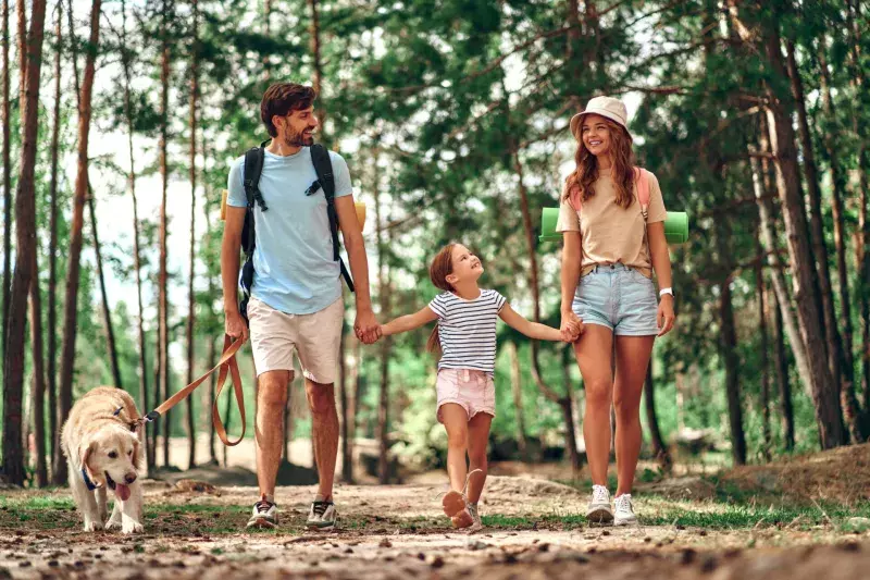 Man and children walking a dog through the forest.