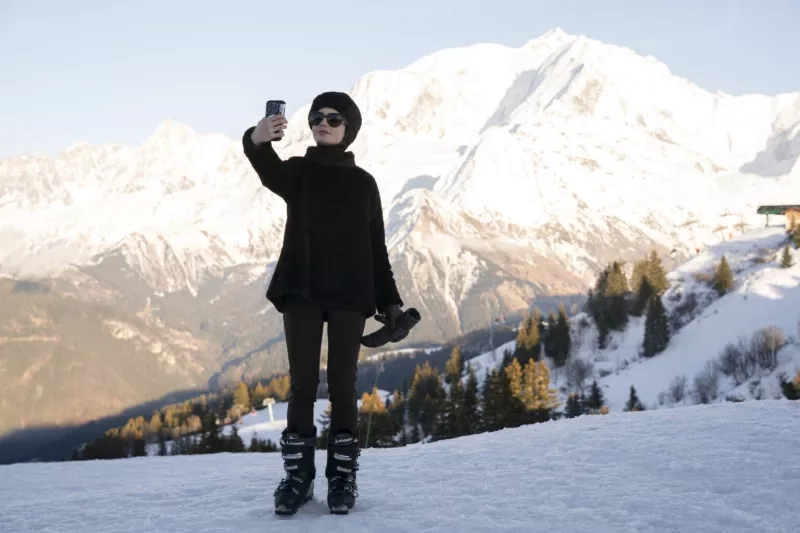 A woman standing on a skislope taking a selfie