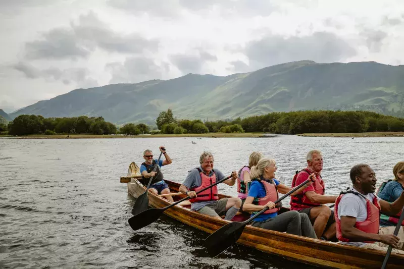 Team all rowing together on the Derwent Water cheering each other on.