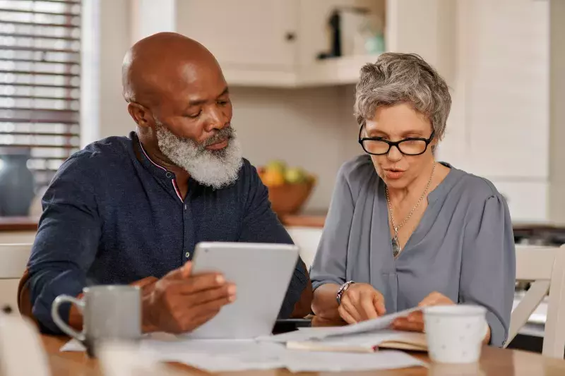 Cropped shot of a senior couple using a digital tablet while going over bills and paperwork together at home