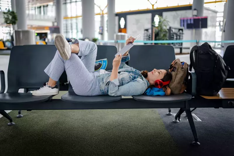 Young Woman waiting for delayed flight and reading digital book on chairs stock photo