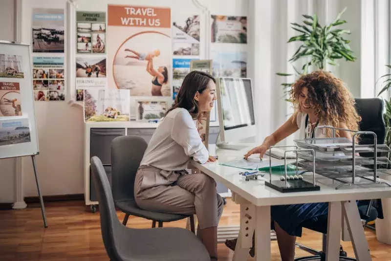 woman in modern travel agency talking with a female travel agent, she is planning a vacation..