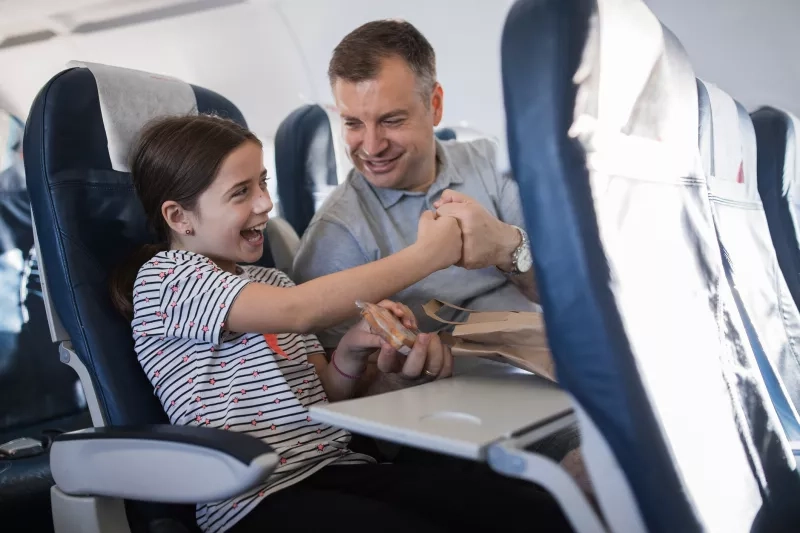 Smiling young girl taking a sandwich from her father's hands and fist bumping with him for fun