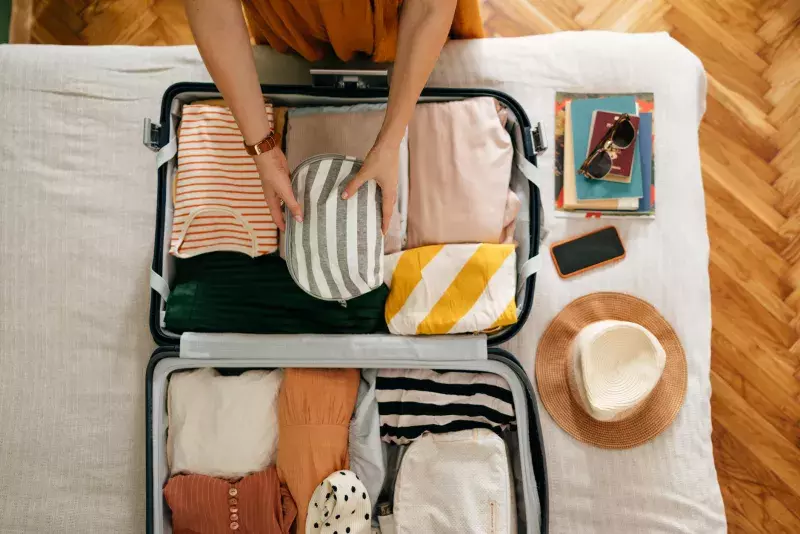 Cropped Photo of an Unrecognizable Woman Putting a Cosmetic Bag in Her Suitcase