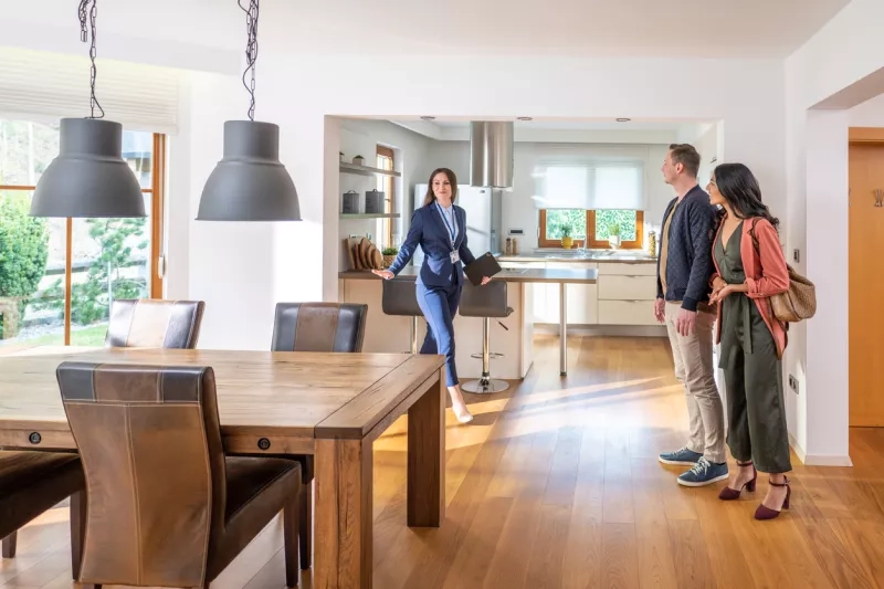 female real estate agent showing couple modern kitchen and dining room