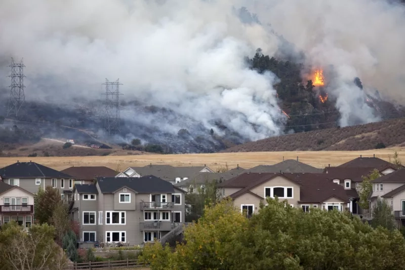 Wildfire burns in the hills behind a row of homes.