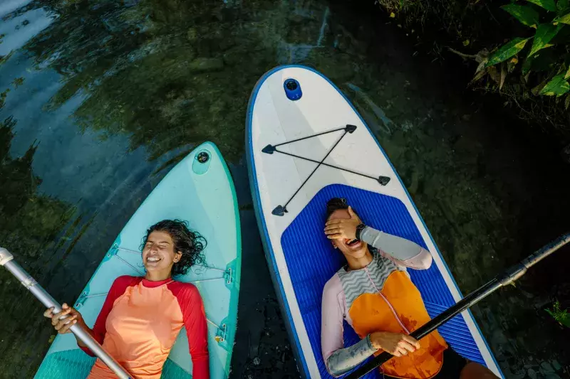 two teenage girls lying on their stand-up paddleboards and having a great time