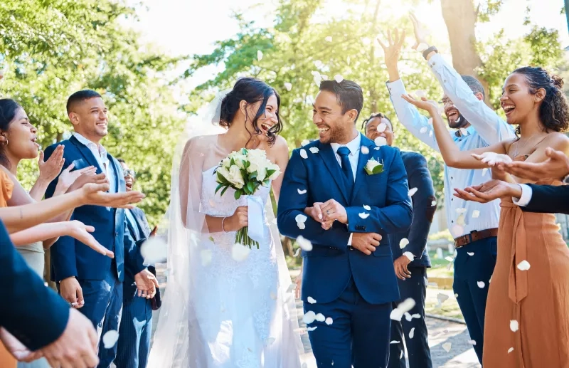 Wedding guests throwing rose petals confetti tradition over bride and groom