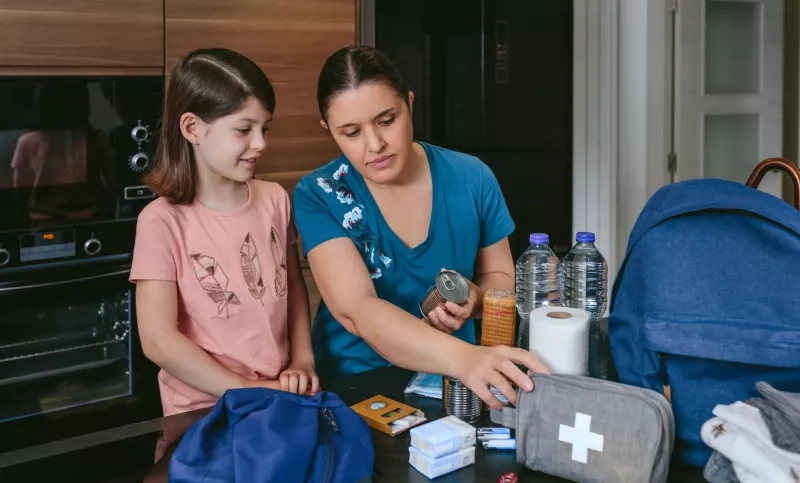 Mother preparing emergency backpack with her daughter