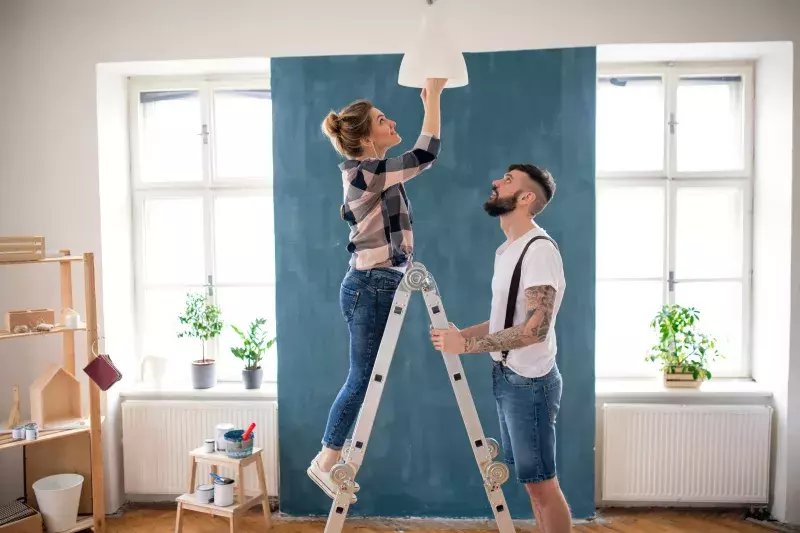 Mid adults couple changing light bulb indoors at home, relocation and diy concept