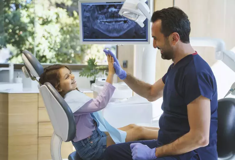 Dentist giving a high five to a little girl at dental clinic