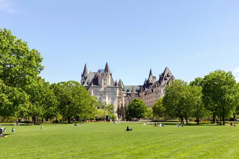 Ottawa, Canada - May 18, 2022: People in Majors Hill Park in spring. Fairmont Chateau Laurier Hotel building in city park in downtown.