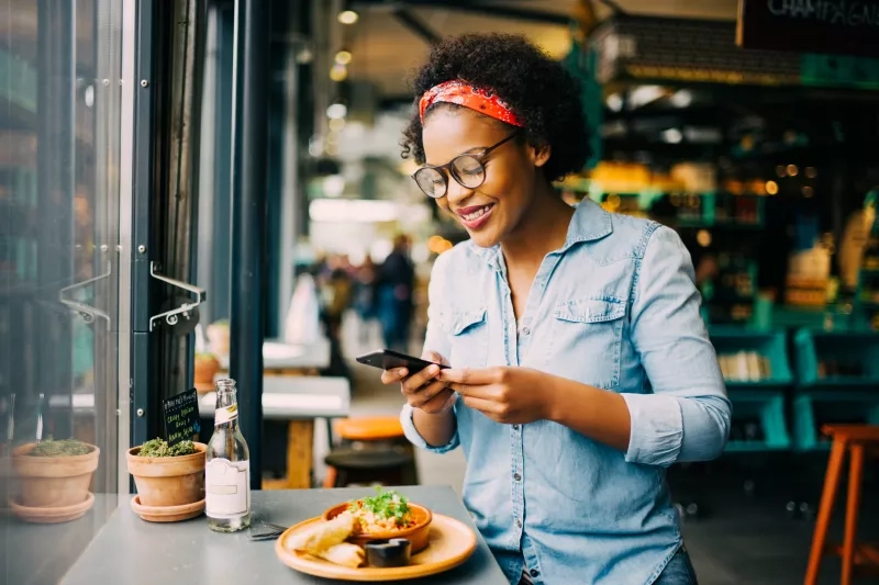 Smiling woman taking photos of her food in a cafe stock photo