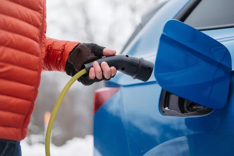 Close up of charging electric car during cold snowy day