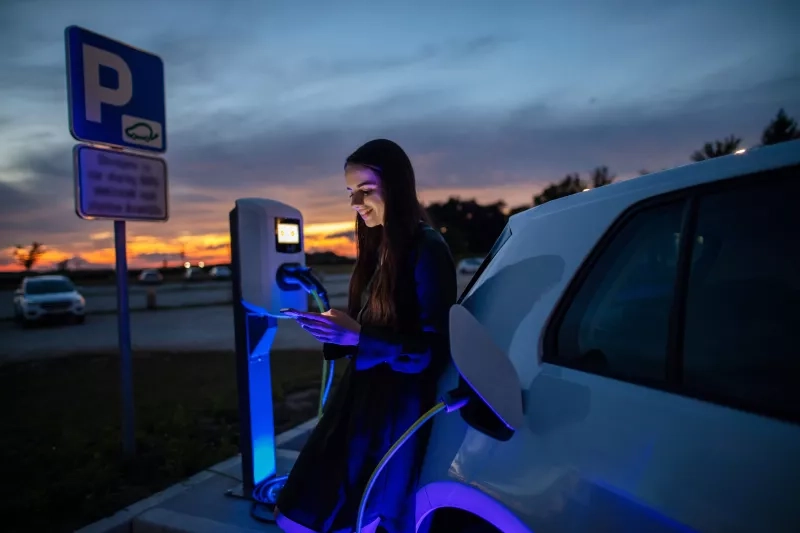 Woman charging her electric car at night