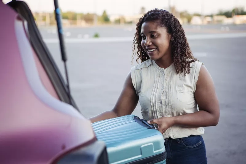 Women putting suitcase in car