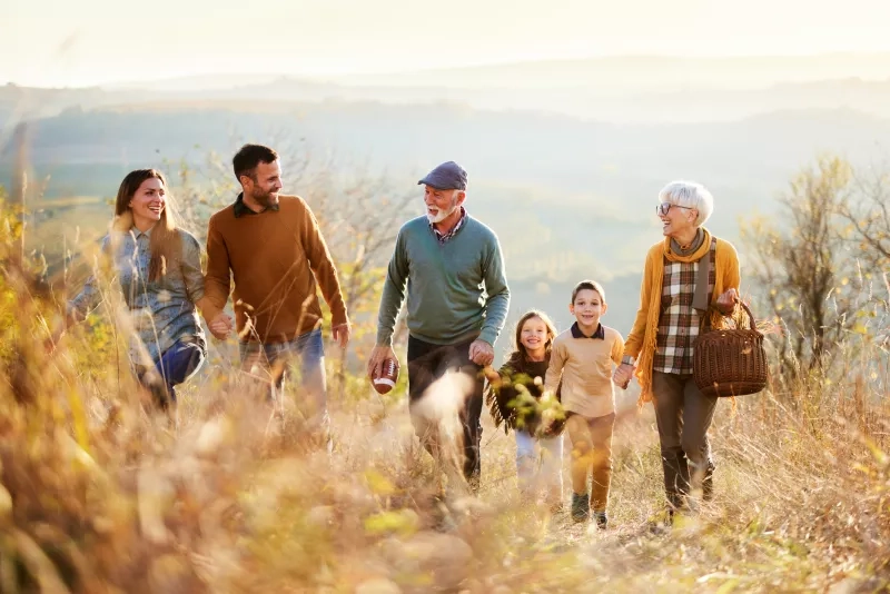 Happy extended family talking in autumn while going for a walk