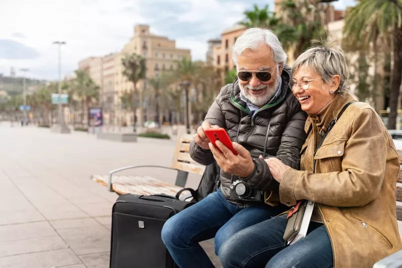  senior couple tourists traveling together using cell phone