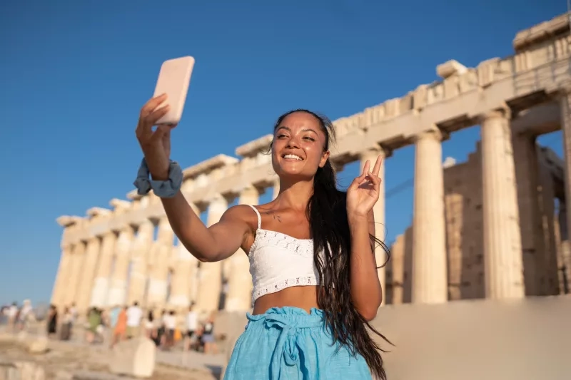 woman taking selfie with her mobile phone in front of the Acropolis of Athens