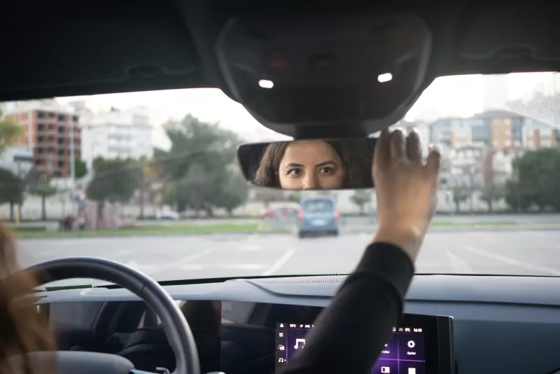 woman adjusting a rear view mirror