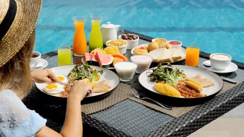 woman eating breakfast next to the pool