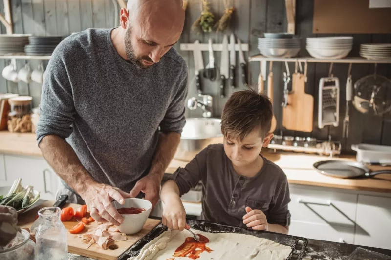 Father with kid preparing pizza at home