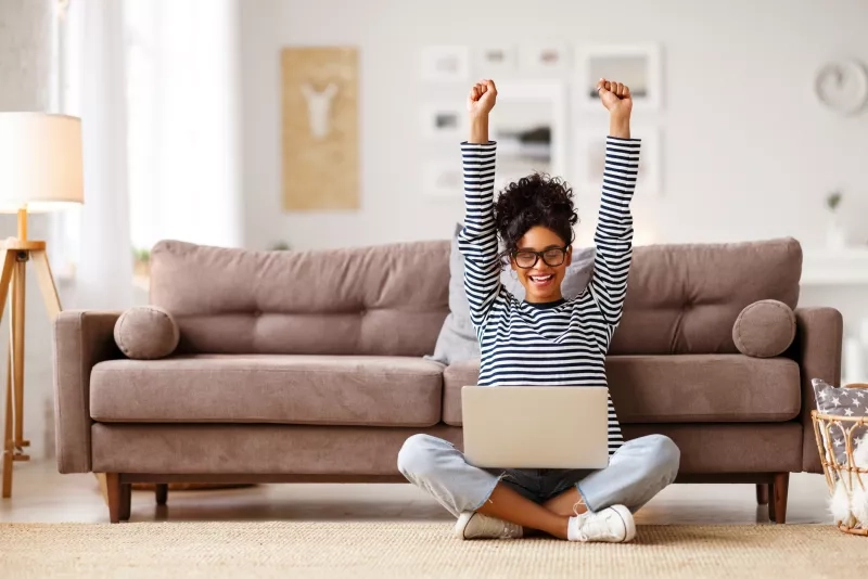 woman celebrating good news while working on laptop