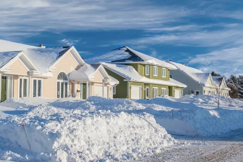 Snow piled up along a plowed road in a northern suburb
