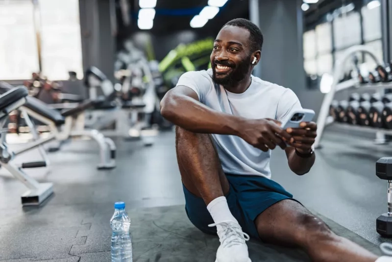 Man resting with smartphone in gym