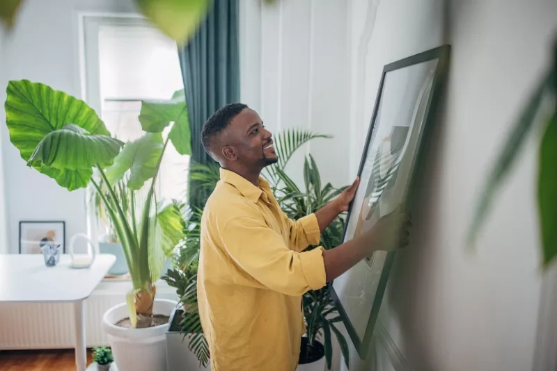man decorating his living space with artwork