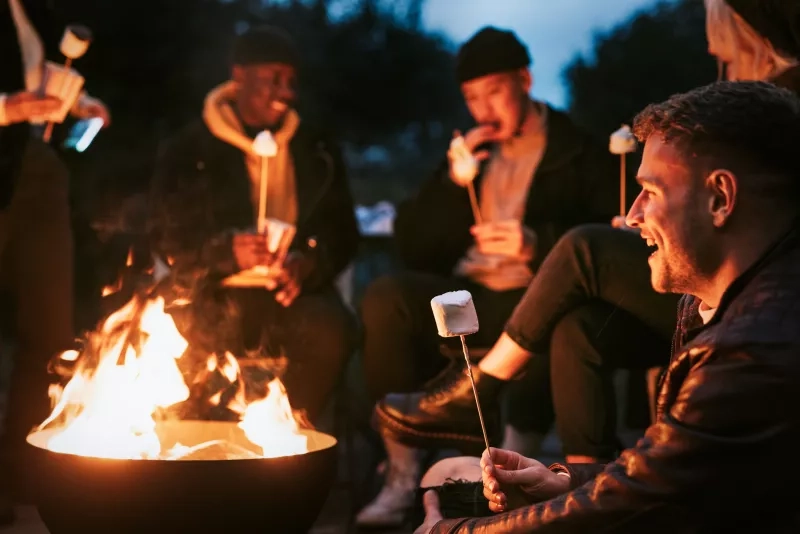 Friends enjoying s'mores and marshmellow together by the bonfire