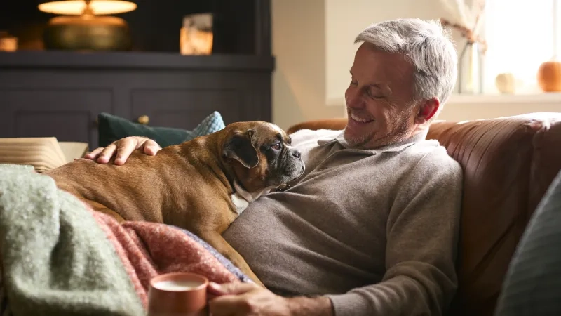 Man at home with a cup of tea and his dog