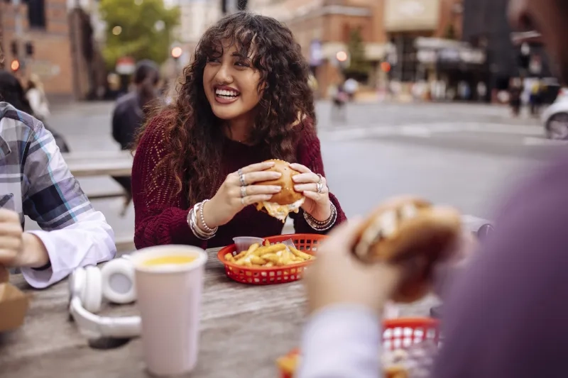 teenage girl sitting at fast food restaurant with burger