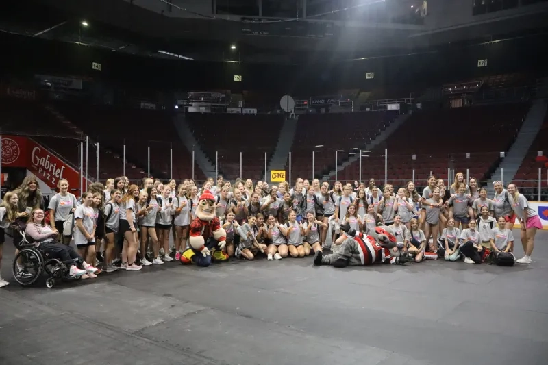 A large group of girls smile at the camera slongside Ottawa REDBLACKS mascott, Big Joe, and Ottawa 67s mascott Reilly