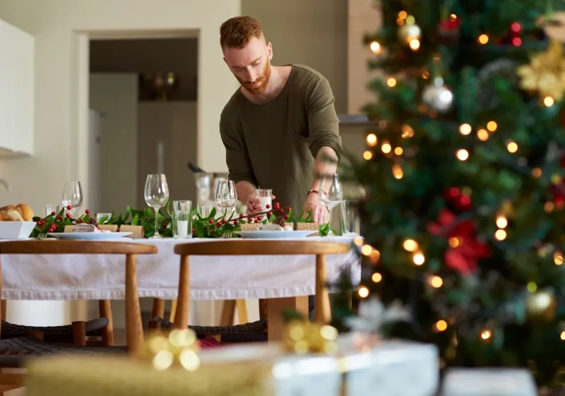 man setting a table for a Christmas party at home