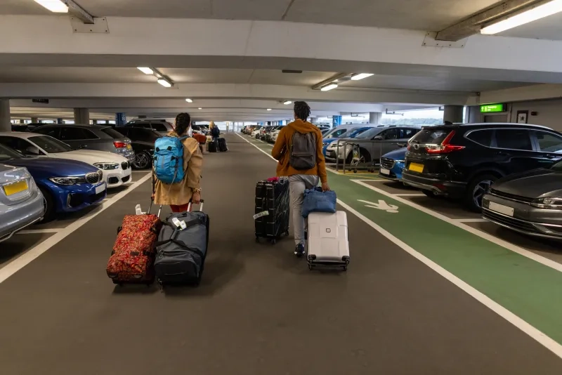 two people with luggage in airport parking lot