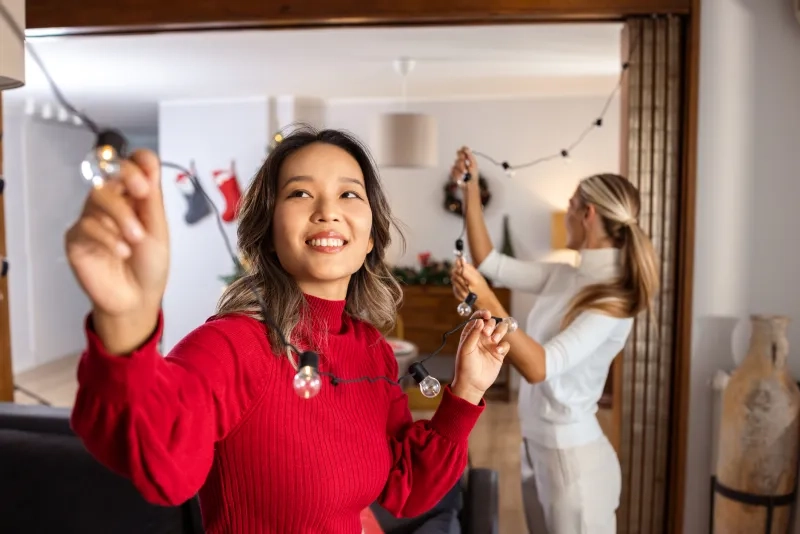 two women decorating a cozy living room for Christmas