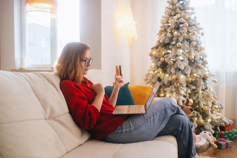 woman making reservation on laptop next to a Christmas tree