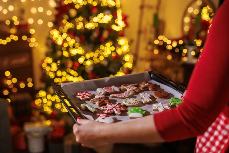 person holds a baking tray of decorated Christmas cookies,