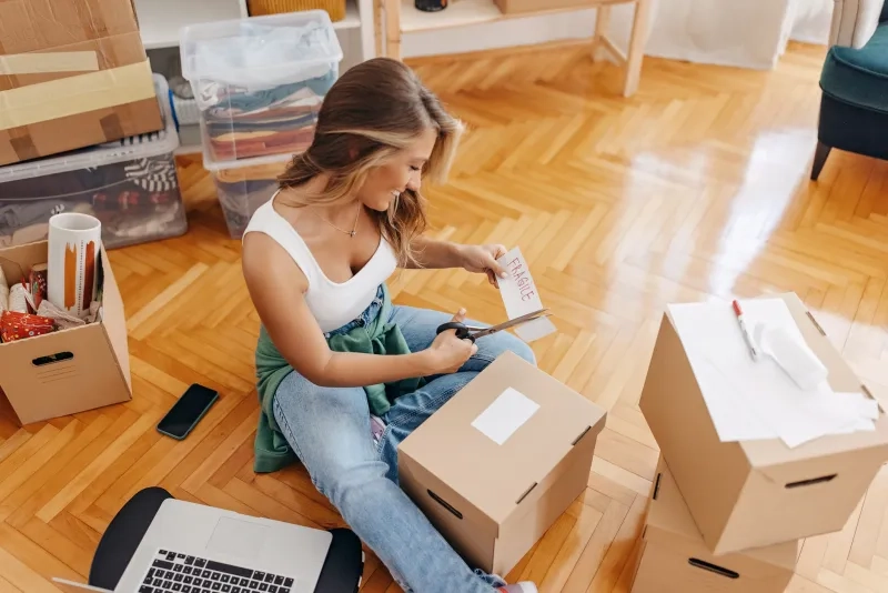 woman using scissors to cut fragile label on the living room floor.