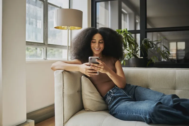 Woman sitting on couch looking at phone