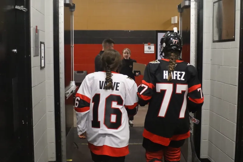 Two young hockey playerswalk away from the camera