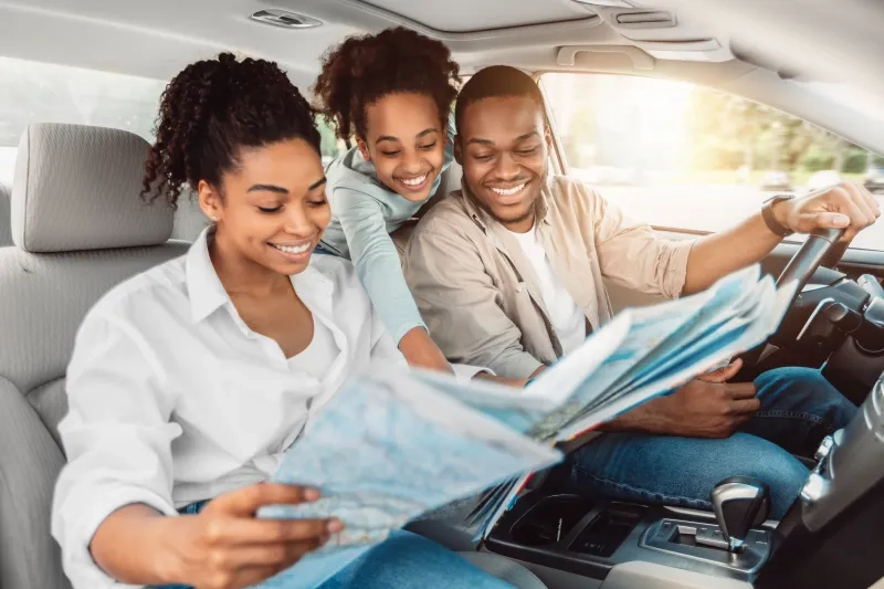 Family looking at road map sitting in car 