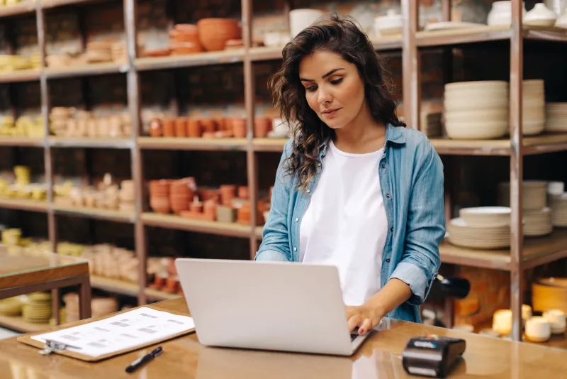 ceramic shop owner using a laptop in her store