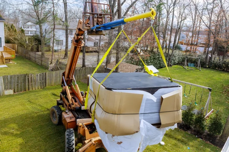 forklift holding a hot tub over a yard