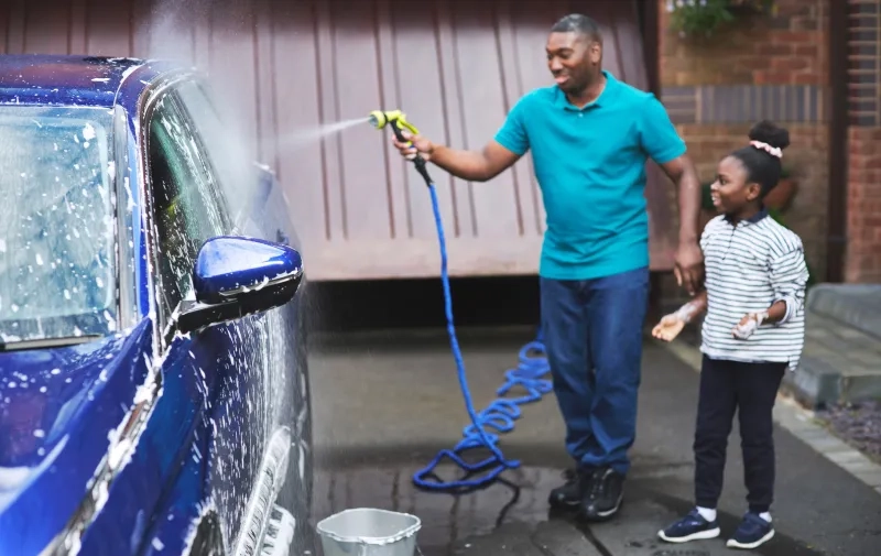 father and daughter washing a car