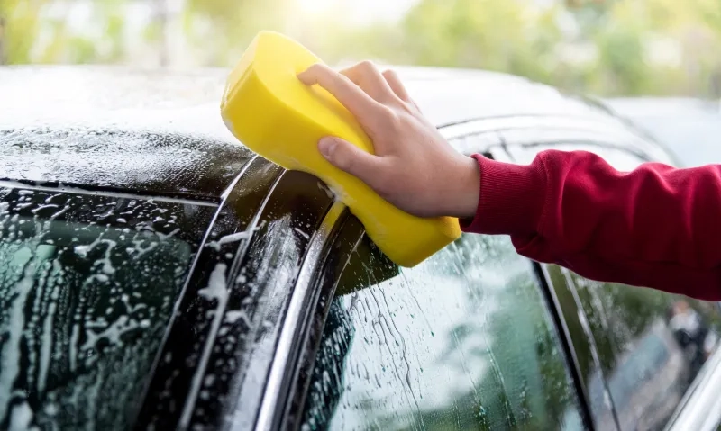 hand holding sponge washing car