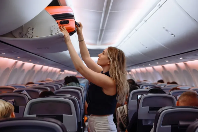 Passenger putting hand baggage in overhead bin on airplane