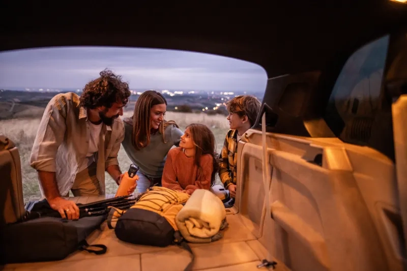 Family unpacking car trunk